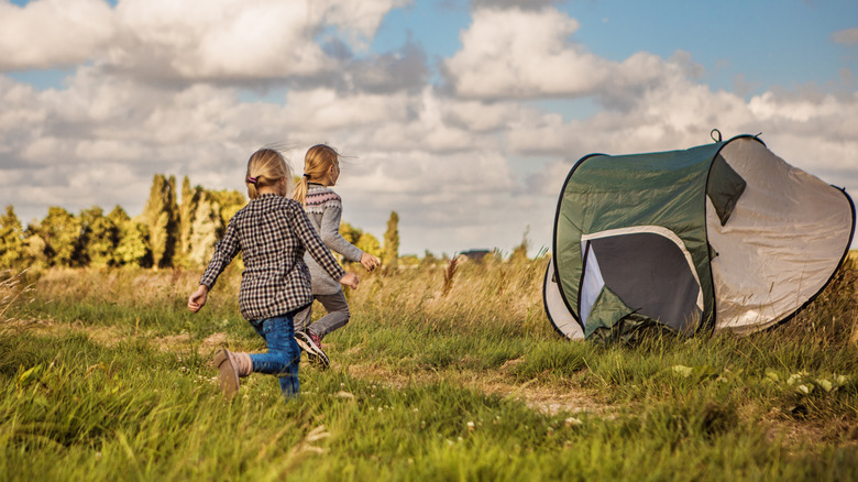 Two children chase after a tent that's been blown away by the wind