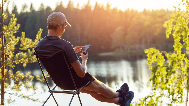 A man sits on a campchair beside the water