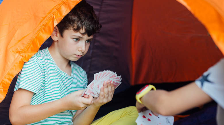 A kid playing cards in a tent