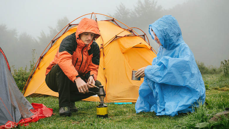 Campers in rain gear trying to make a coffee