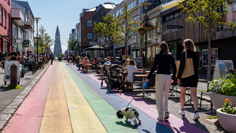 Women walking a dog down a rainbow street in Reykjavik, Iceland, ending at the cathedral
