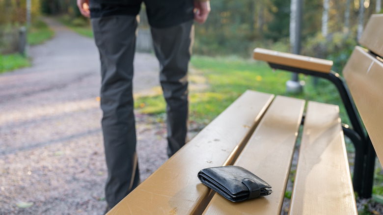 A man walks away from a bench, leaving his wallet behind