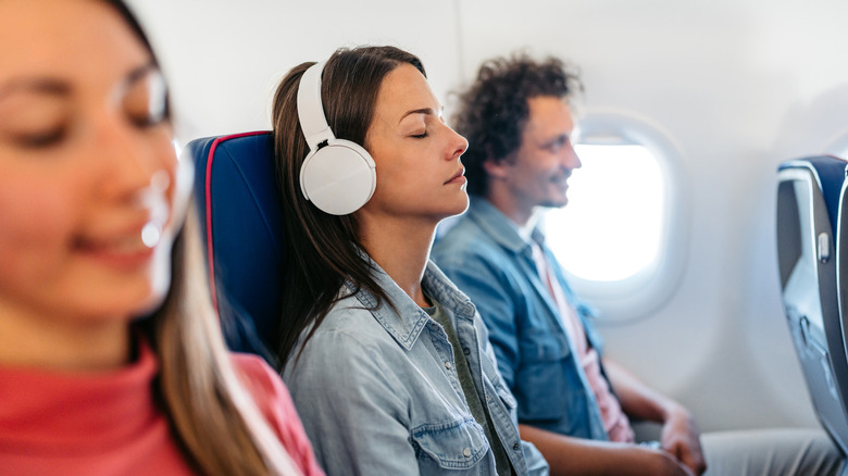 Someone sleeping with headphones on a plane