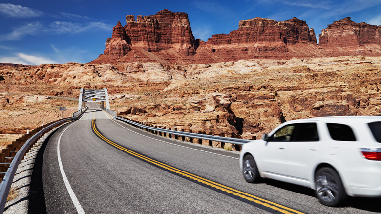 White car drives on road to red rocks Utah