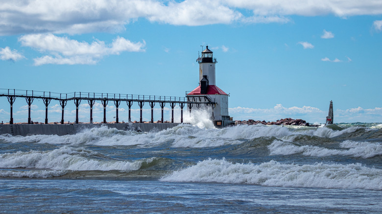 The Michigan City lighthouse on a windy summer day with blue skies and big waves