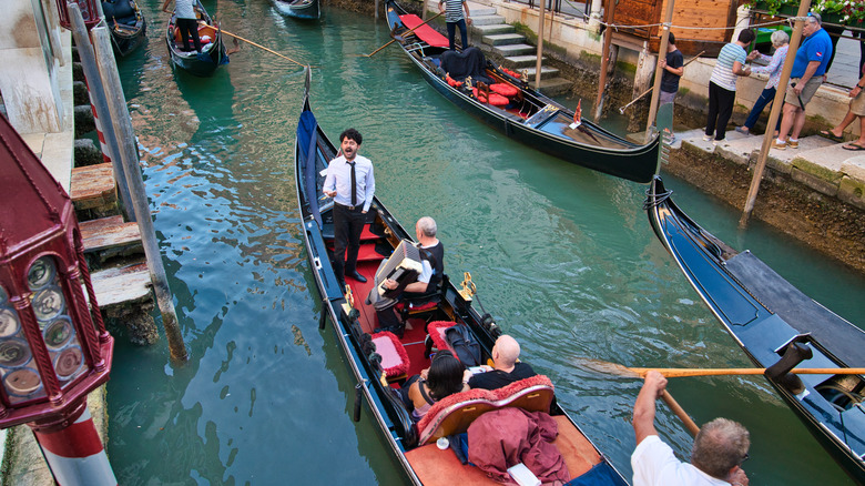 Man sings on gondola while another man plays accordion in Venice canal