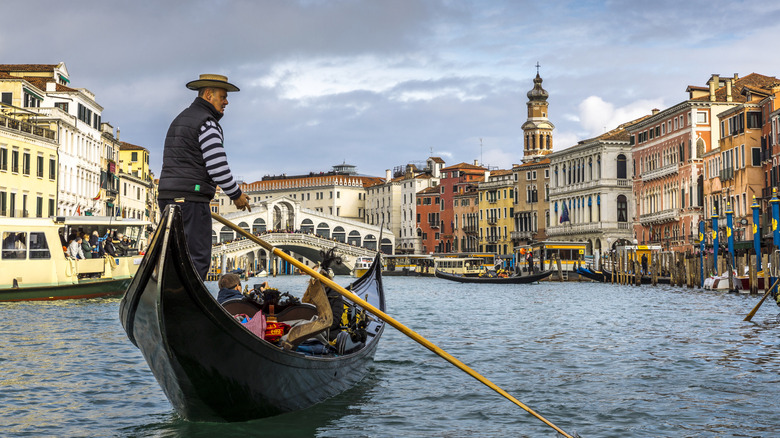 Gondolier rows in the Grand Canal on a cloudy day in Venice