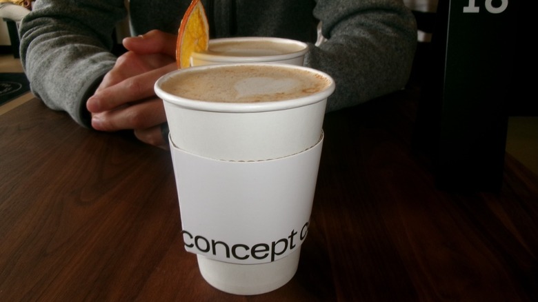 A man folds his arms in front of two paper cups of coffee at Concept Coffee in Sacramento.