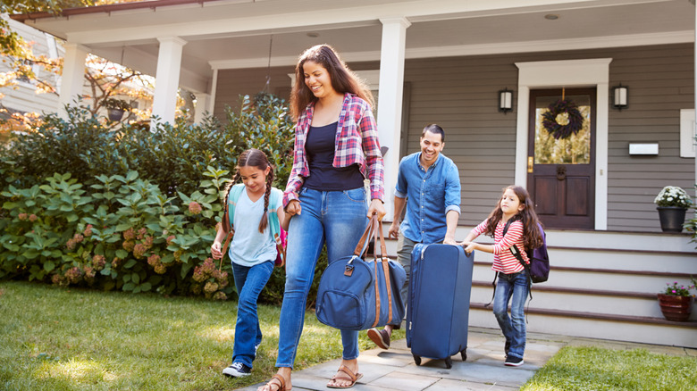 Family leaving the house for vacation with a duffel bag and suitcase
