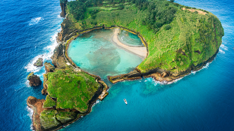 Bird's-eye view of a volcanic island cradling a natural pool and surrounded by the sea