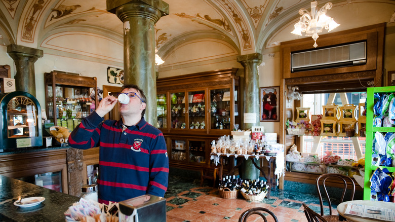 A man sipping an espresso while standing in an Italian coffee bar