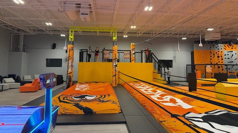 A large, indoor trampoline park with orange crash pads.