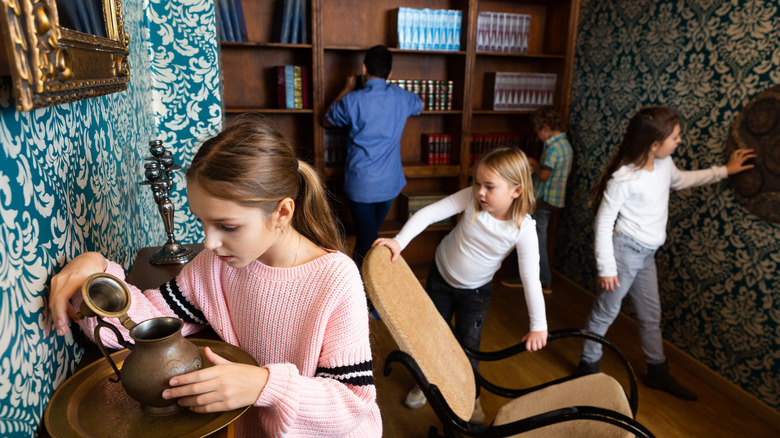 Kids examine furniture in a Victorian-themed escape room.