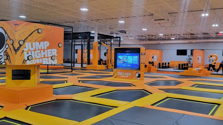 A floor covered in trampolines and orange padded decor and furniture at an indoor trampoline park.