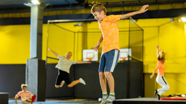 A young boy jumps on a huge indoor trampoline.