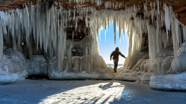 A person exploring the ice caves in a tunnel at the Apostle Islands with icicles hanging all around