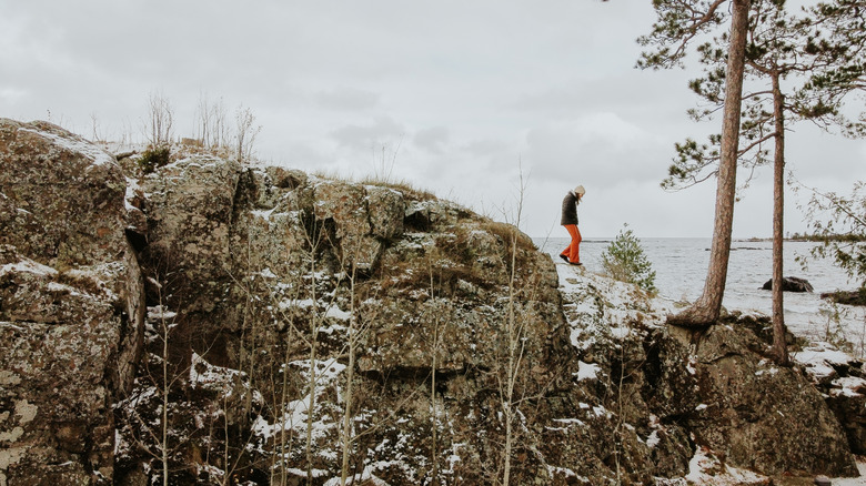 A woman walking on a snowy rock on Lake Superior's shore with the lake in the background