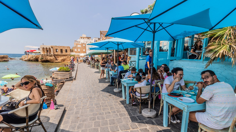 A group of tourists sitting along the seaside promenade at a restaurant in Lebanon