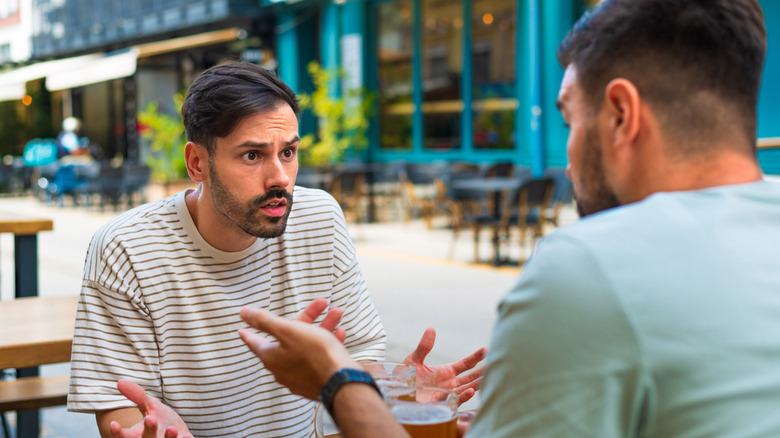 Two people arguing at an outdoor restaurant table