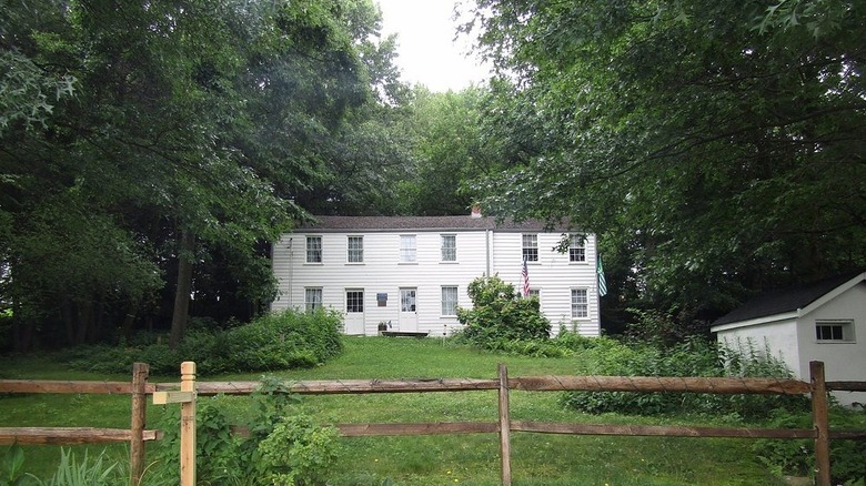 Rachel Carson Homestead, a two-story house with white siding surrounded by grass and trees, behind a wooden fence