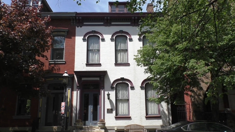 Gertrude Stein birthplace, a white-painted two-story row house with a blue door and maroon accents, and a wooden bench out front