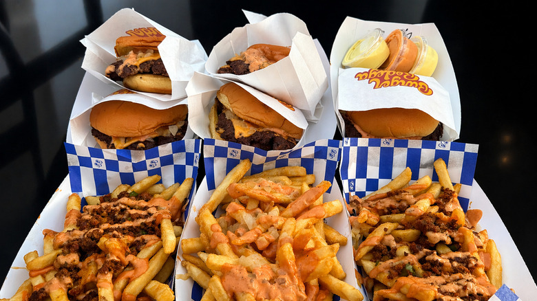 A table consisting of burgers and fries at Burger Bodega in Houston with various toppings