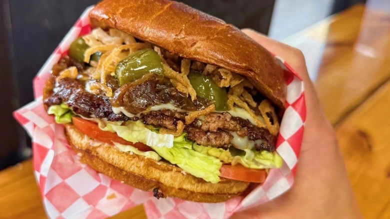 A burger from burgerchan with multiple toppings held up by a hand