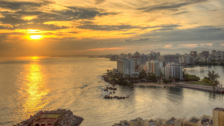An aerial view of coastal San Juan cityscape during bright cloudy sunrise