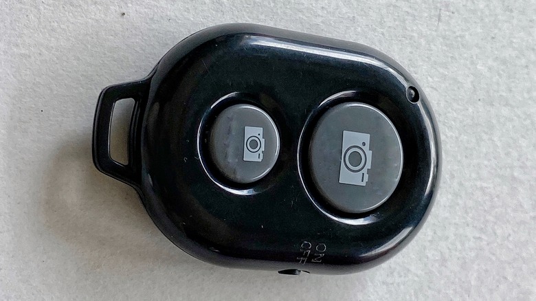 A close-up of a small black wireless remote that can be used to control a cell phone's camera features