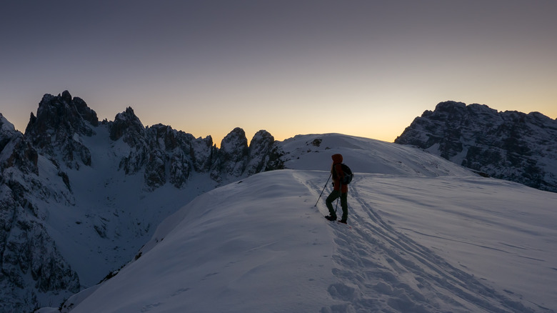 A person snowshoeing on a mountaintop at dawn
