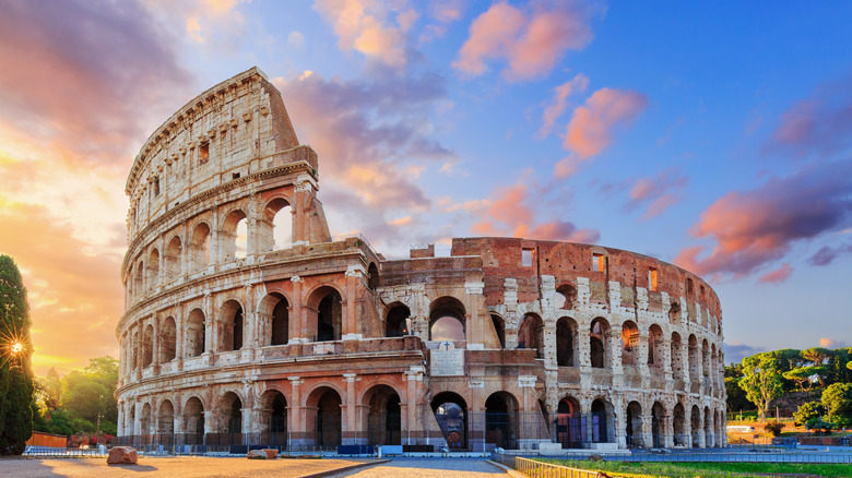 view of ancient Colosseum in Rome against colorful sky
