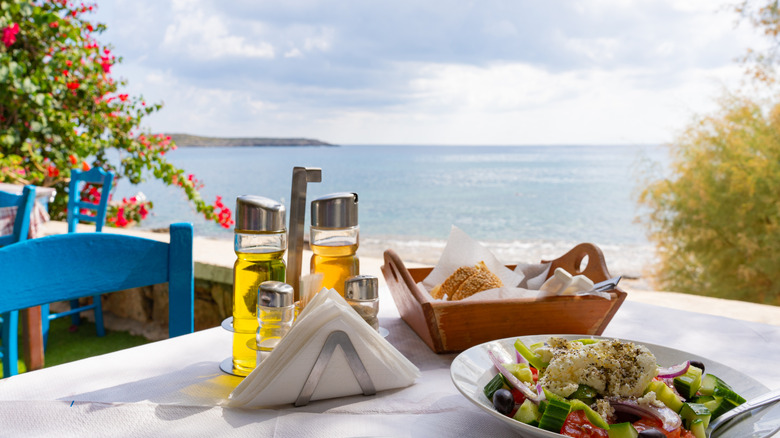 A set table with Greek salad overlooking the water