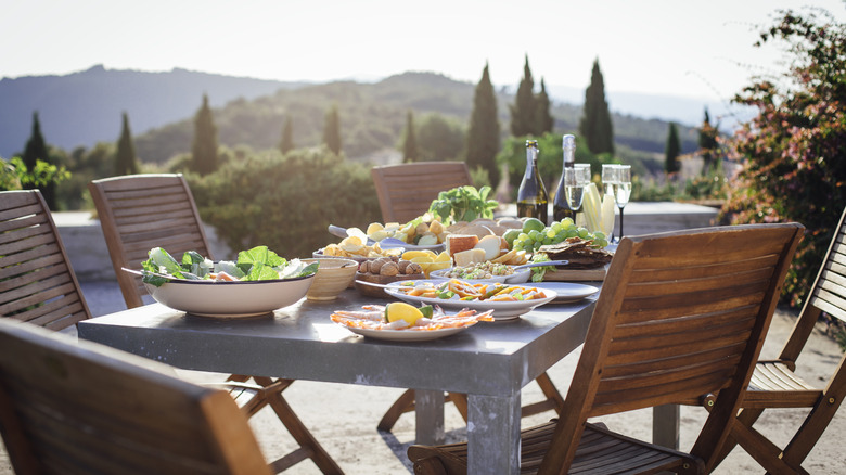 An outdoor table set with food overlooking green hills