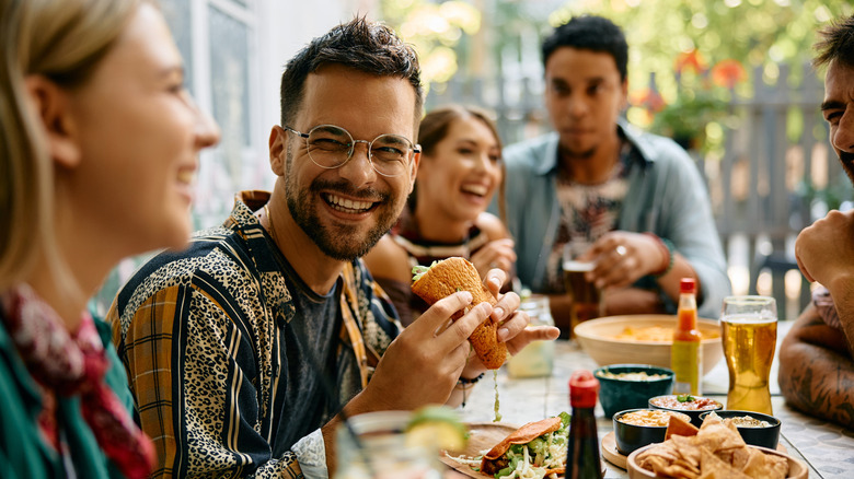 A smiling man holds a taco at a restaurant in Mexico
