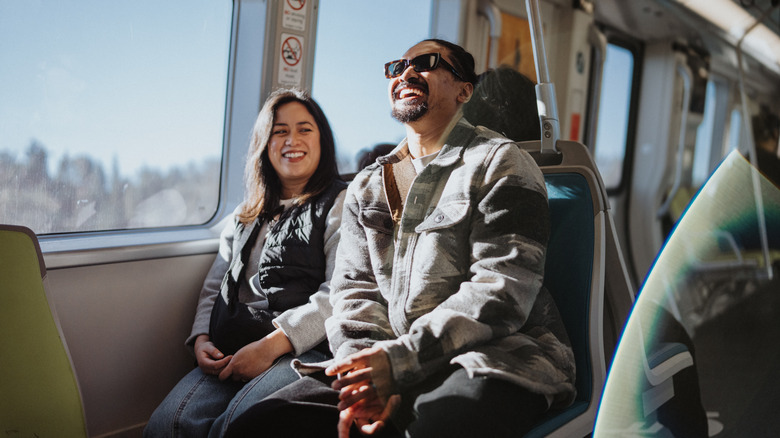 Two travelers laughing while on public transportation