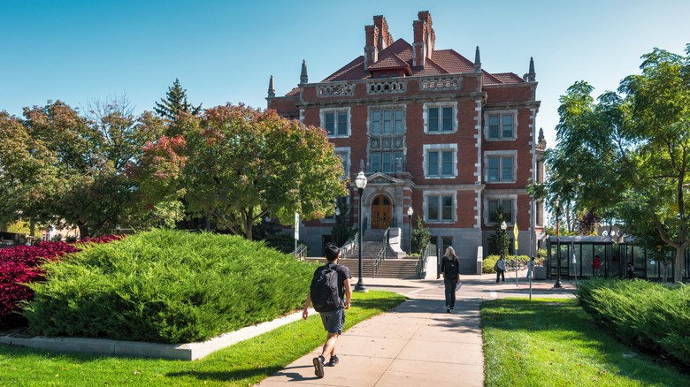 Students walking through the grassy and leafy campus of the University of Minnesota with a grand building in the background