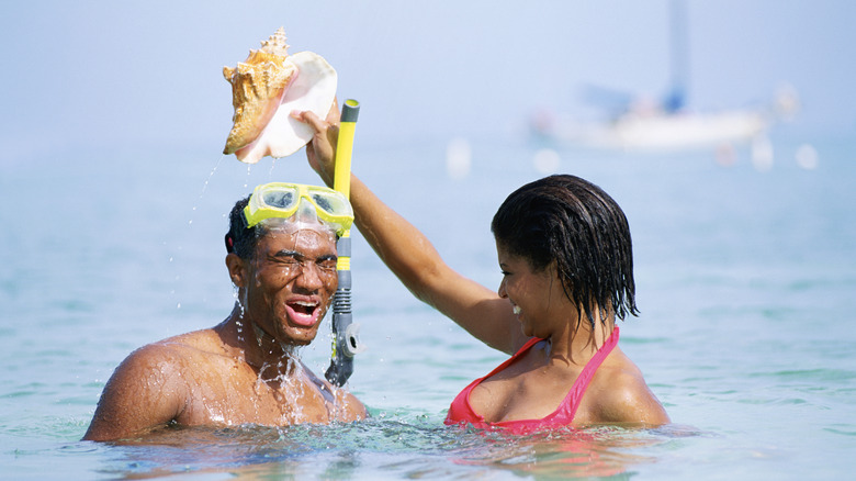 A woman dumping water on a man's head while snorkeling
