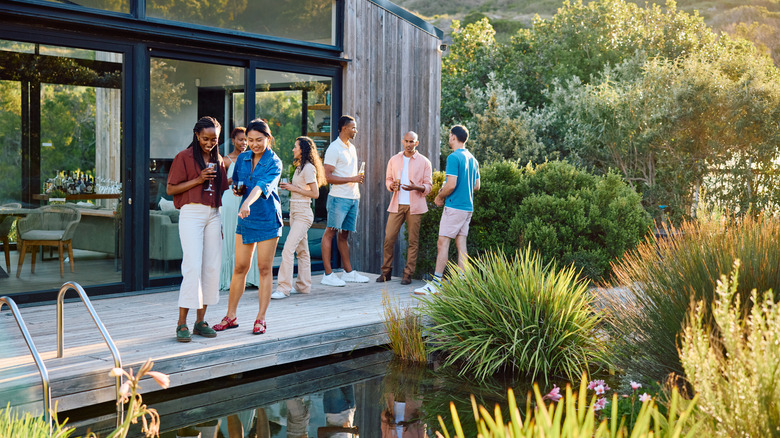 Group of friends standing outside a home surrounded by lush greenery