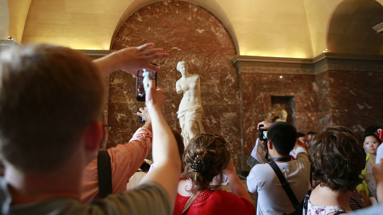 A crowd of tourists photographing Venus de Milo at the Louvre