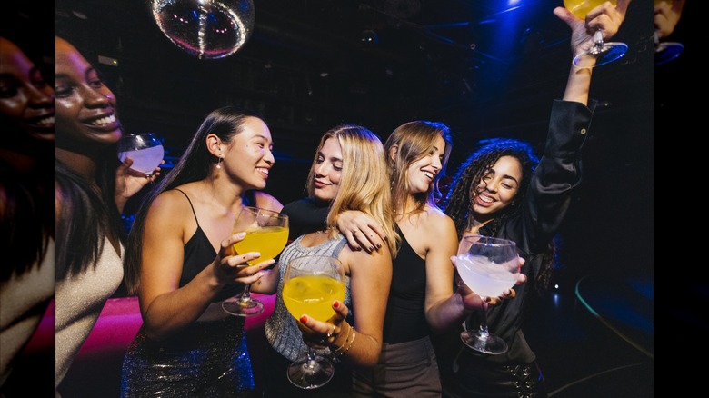 Friends dance with cocktails in their hands