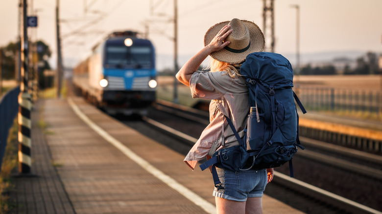Woman with a backpack looking at an approaching train