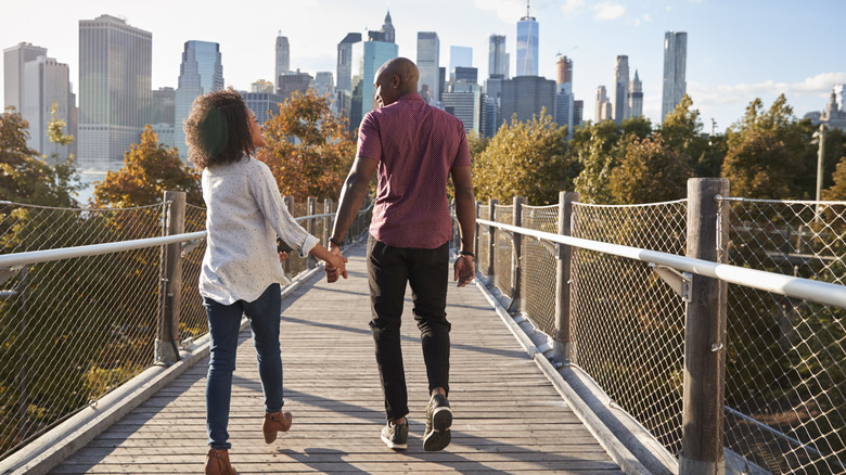 A young couple on a bridge with a city skyline in the background