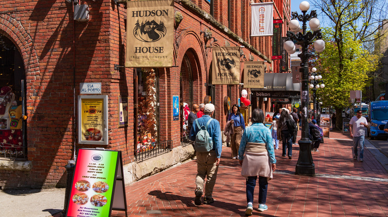 Tourists walking on red tiled streets along red brick buildings with shop signs on a sunny day