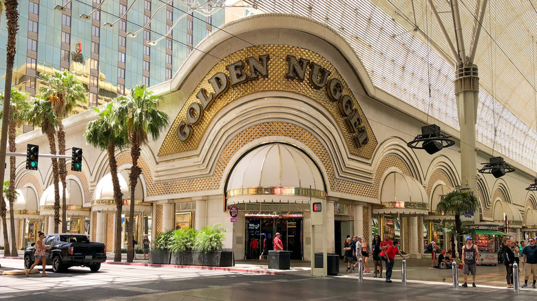 The historic facade of The Golden Nugget with palm trees and people outside
