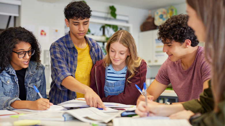 Diverse teenagers crowd around homework