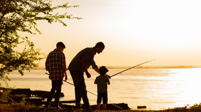 A dad fishing with his two children at the lake