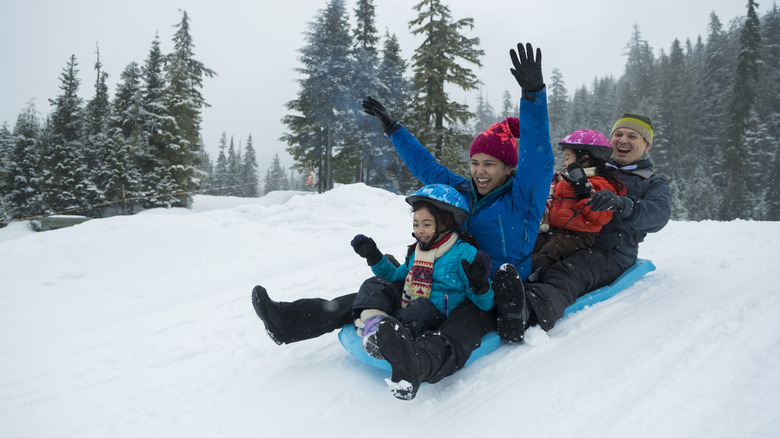 A family sledding down a snowy slope together