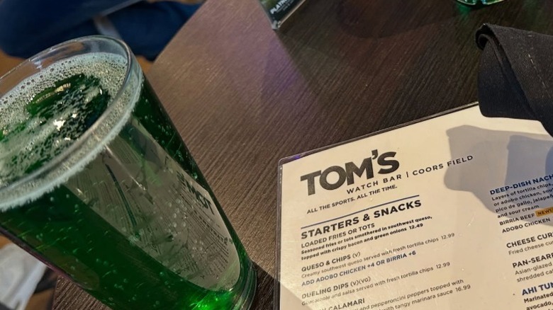 The Tom's Watch Bar menu next to a green beer on a table.