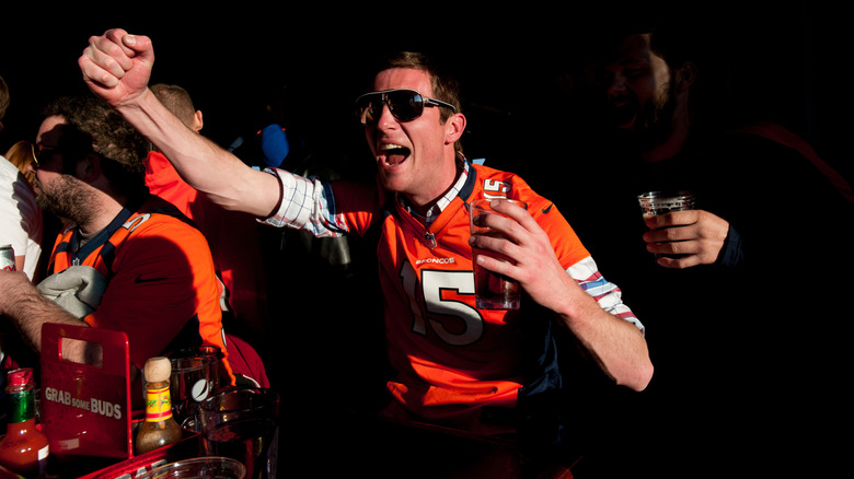 A Denver Broncos fan cheering on the team while holding a beer in the sunshine at ViewHouse.