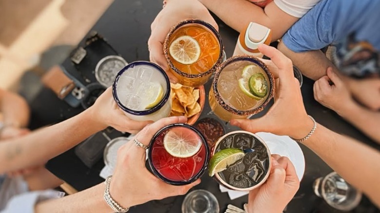 Five friends holding margaritas of different colors up together at Federales in Denver